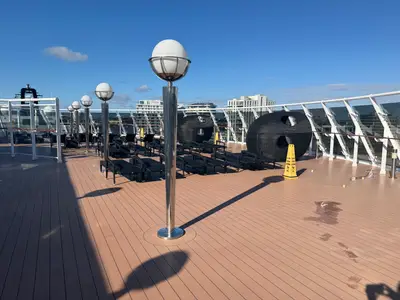 Das moderne Sonnendeck an Bord der MSC Preziosa bietet Liegen, kugelförmige Lampen und einen Blick auf die Skyline.