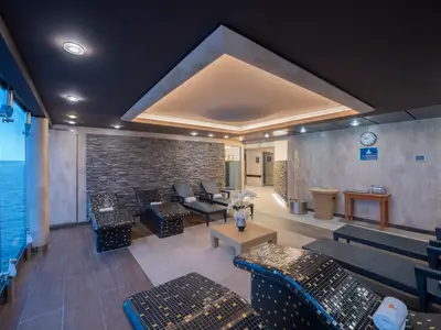 Entspannungsraum des MSC Aurea Spa an Bord der MSC Preziosa. Moderne Liegen, Steinwand und Glasfront mit Meerblick. Indirekte Beleuchtung schafft eine ruhige und einladende Atmosphaere.