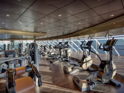 Ansicht des lichtdurchfluteten Technogym Fitnessstudios an Bord der MSC Preziosa mit zahlreichen Cardio- und Kraftgeräten und Panoramafenstern zum Meer.