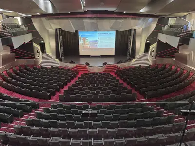 Blick von oben in das leere, moderne Theater an Bord der MSC Preziosa mit rotem Teppich und großer Bühne.