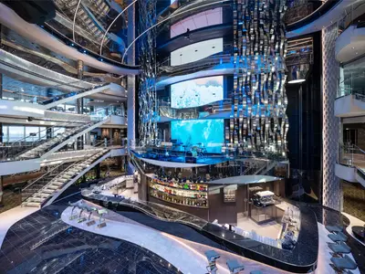 Das prunkvolle Atrium der MSC Seascape zeigt die Seascape Bar, eine Bühne, glitzernde Swarovski-Treppen und große LED-Bildschirme. Moderne Gestaltung mit blauen Akzenten dominiert.
