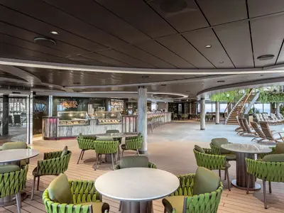 Die helle Jungle Beach Bar an Bord der MSC Seascape, mit grünen Sitzen, Tresen und Poolbereich. Meerblick, Holzdetails und Pflanzen.