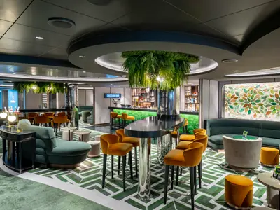 Die stilvolle Cocktail Bar an Bord der MSC Seascape. Grüne Fliesentheke, goldene Barhocker und bequeme Sessel laden zum Verweilen ein. Die Decke ist mit üppigen Hängepflanzen dekoriert.