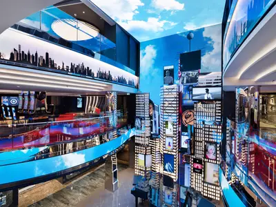 Innenansicht des futuristischen Times Square Atriums an Bord der MSC Seascape mit Leuchtreklamen, Digitalbildschirmen, einer Stadtsilhouette und Casino-Bereich.