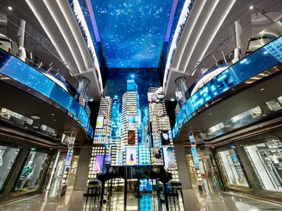 Blick in das moderne, elegant beleuchtete Atrium der MSC Seascape mit einem Konzertflügel und einer mehrstöckigen digitalen Skyline-Darstellung an der Wand.