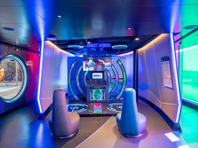 Moderner VR-Spielbereich Beat Hero an Bord der MSC Seascape mit bunten Lichtinstallationen und zwei Spielstationen. Ein rundes Fenster zeigt einen Außenbereich.