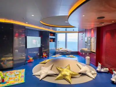 Ein bunter Baby Club Chicco an Bord der MSC Seascape, ausgestattet mit Spielzeug, weichen Matten und einer großen Fensterfront mit Blick auf das Meer. Ideal für kleine Kinder.