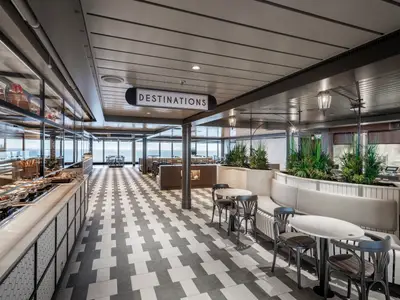 Modernes Marketplace Buffet & Restaurant der MSC Seascape. Lange Buffettheke, Sitzbereiche, große Fenster mit Meerblick. Gemusterter Boden. Helle, entspannte Atmosphäre, ohne Personen.