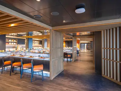 Spezialitätenrestaurant Kaito Sushi Bar an Bord der MSC Seascape. Elegantes Interieur mit Holzlamellen, Theken, orangefarbenen Stühlen und angerichteten kleinen Speisen.