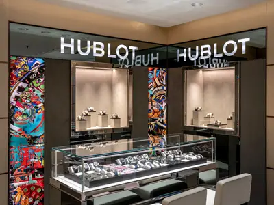 Innenaufnahme des Hublot TimeVallée Shops an Bord der MSC Seascape. Gläserne Vitrinen präsentieren luxuriöse Armbanduhren. Moderne Einrichtung mit Kunstpaneelen, warm beleuchtet.
