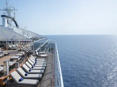 Das weitläufige Sonnendeck der MSC Seascape mit vielen Liegestühlen und blauen Handtüchern. Der Blick öffnet sich zum weiten, glitzernden blauen Meer unter einem klaren Himmel.