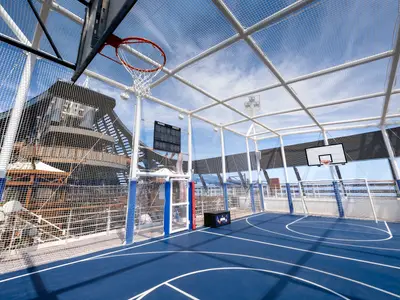 Die Sports Arena an Bord der MSC Seascape. Ein blauer Basketball- und Multisportplatz auf dem Deck, umgeben von Schutznetzen. Blauer Himmel, keine Personen.