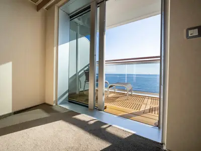 Helle, barrierefreie Balkonkabine an Bord der MSC Seashore. Eine Glasschiebetür führt zum Balkon mit Sitzgelegenheiten und dem weiten, offenen Meer.
