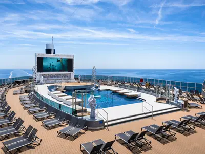 Der Long Island Pool Bereich an Bord der MSC Seashore mit grosser Leinwand und zahlreichen Liegen. Im Hintergrund ist das weite Meer sichtbar.