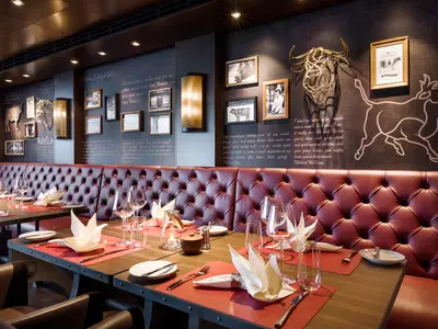 Innenansicht des Spezialitätenrestaurants 'Butcher's Cut' an Bord der MSC Seashore. Rote Lederbänke, dunkle Wände mit Bullen-Skulpturen und gerahmten Bildern. Tische sind elegant gedeckt.