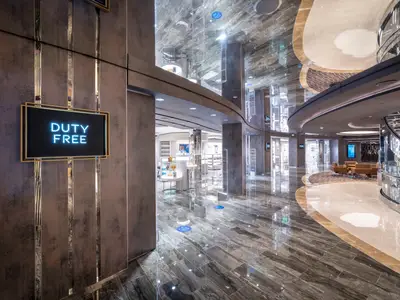 Eine luxuriöse Ladenpassage an Bord der MSC Seashore mit einem beleuchteten "DUTY FREE"-Schild. Der Innenraum ist modern, mit glänzendem Marmorboden, reflektierenden Decken und stilvoller Beleuchtung.