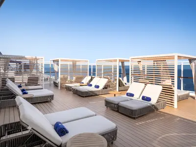 Ein luxuriöses Sonnendeck an Bord der MSC Seashore mit zahlreichen bequemen Sonnenliegen, modernen Cabanas mit Meerblick und blauer Himmelkulisse.