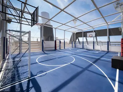 Die Sports Arena an Bord der MSC Seashore: ein blauer Multisportplatz mit Basketballkörben und Fußballtoren, gesichert durch Netze und überdacht. Der blaue Himmel ist sichtbar.