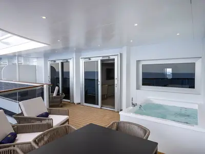 Ein luxuriöser Außenbereich einer Royal Suite an Bord der MSC Seashore. Man sieht einen Whirlpool mit sprudelndem Wasser, eine Essecke und komfortable Loungesessel. Im Hintergrund ist das offene Meer zu erkennen.