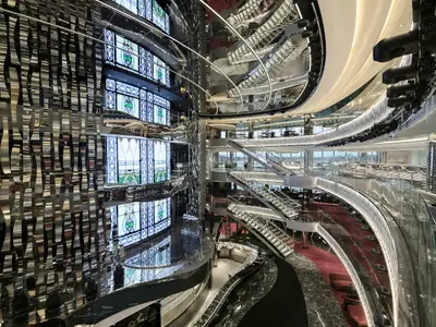 Blick ins luxuriöse, mehrstöckige Atrium der MSC Seaside mit LED-Treppen, reflektierenden Oberflächen und farbigen Digitaldisplays. Modernes Design prägt den weitläufigen Innenbereich.