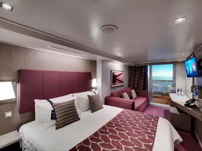 Gemütliche Balkonkabine an Bord der MSC Seaside. Der Raum verfügt über ein Doppelbett, ein Sofa, einen Schreibtisch und einen Balkon mit Meerblick.