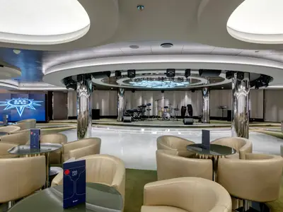 Blick in die moderne Haven Lounge an Bord der MSC Seaside mit einer zentralen Bühne, Instrumenten und gemütlichen Sitzgruppen.