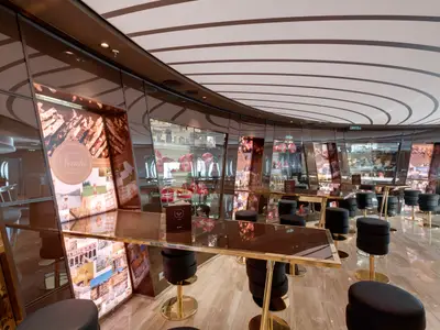 Innenansicht der Venchi 1878 Chocolate Bar an Bord der MSC Seaside. Elegante Theken, schwarze Barhocker und spiegelnde Oberflächen reflektieren Schokoladenpräsentationen.