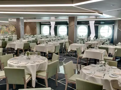 Blick in das Ipanema Restaurant an Bord der MSC Seaside. Zahlreiche elegant gedeckte Tische mit hellgrünen Stühlen in einem modernen Ambiente.