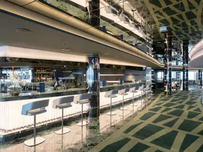Die elegante Shine Bar an Bord der MSC Seaview. Lange Marmortheke, beleuchtete Front und Barhocker. Spiegelnde Decken und Säulen prägen den modernen Innenraum.