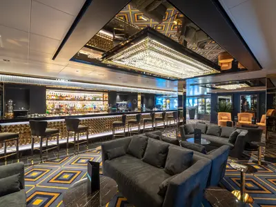 Die luxuriöse Bar-Lounge an Bord der MSC Seaview zeigt eine beleuchtete Bar, dunkle Sofas und einen markanten Gold-Kronleuchter.