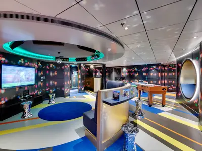 Lebhafter Jugendclub an Bord der MSC Seaview. Mit TV, Spielkonsolen, Tischfussball und Disco-Licht vor bunten Wänden und geometrischem Boden. Ohne Personen.