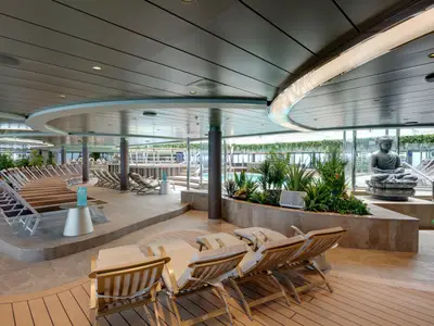 Eine weitläufige, helle Indoor-Poollounge mit zahlreichen Liegestühlen, üppiger Vegetation und einer ruhigen Buddha-Statue an Bord der MSC Seaview. Im Hintergrund ist ein Poolbereich sichtbar.