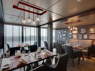 Innenansicht des stilvollen Spezialitätenrestaurants Butcher's Cut an Bord der MSC Seaview mit gedeckten Tischen und Fensterblick.
