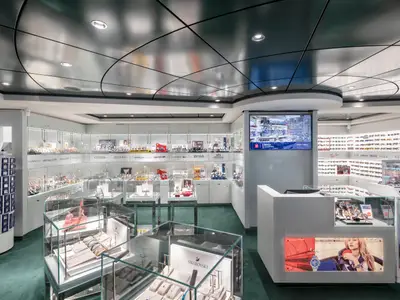 Heller Uhren- und Sonnenbrillenladen an Bord der MSC Seaview. Zahlreiche Glasvitrinen präsentieren Armbanduhren und Sonnenbrillen bekannter Marken. Ein großer Bildschirm zeigt Shop-Informationen.