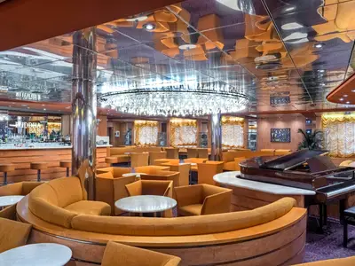 Innenansicht der Buddha Bar auf der MSC Sinfonia mit zahlreichen orangefarbenen Sesseln und Sofas, einem Flügel und einer voll ausgestatteten Bar.