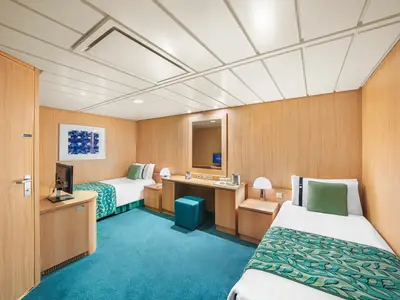 Innenansicht einer barrierefreien Kabine an Bord der MSC Sinfonia mit zwei Einzelbetten, Schreibtisch mit Spiegel und blauem Teppichboden.