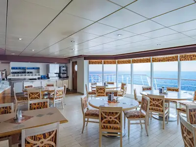 Das Buffetrestaurant La Terrazza an Bord der MSC Sinfonia. Der helle Raum bietet viele Tische, Stühle, eine Buffetstation und große Fenster mit Meerblick.