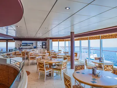 Helles Buffetrestaurant La Terrazza an Bord der MSC Sinfonia. Viele Tische und Stühle, große Fenster mit weitem Meerblick und eine Selbstbedienungstheke im Hintergrund.