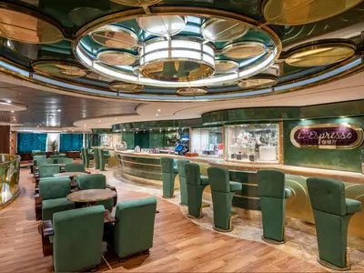 Elegante L'Espresso Bar an Bord der MSC Splendida. Grüne Sessel, Holztische und eine lange, gold-grüne Bar. Auffällige Deckenbeleuchtung. Ohne Personen.