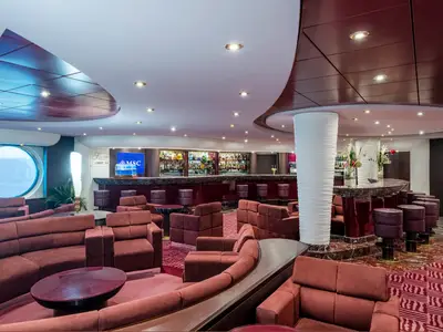 Elegante Splendida Bar an Bord der MSC Splendida. Komfortable rote Sofas und Barhocker in moderner Lounge. Gut bestückte Bar, Bullauge mit Meerblick. Stilvolle Deckenbeleuchtung.