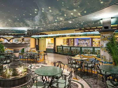 Elegante La Piazzetta Bar der MSC Splendida. Ein Brunnen, gusseiserne Tische und Stühle unter einer Sternenhimmel-Decke. Im Hintergrund ein Bartresen.