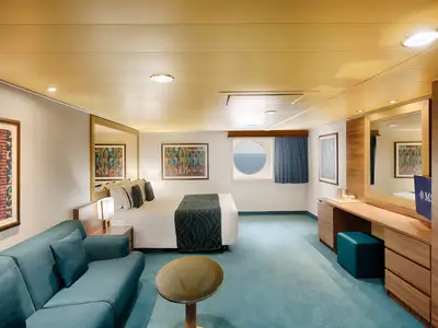 Eine geräumige, barrierefreie Aussenkabine an Bord der MSC Splendida mit Porthole, grossem Bett, Sofa und Schreibtisch. Der Blick geht auf das offene Meer.