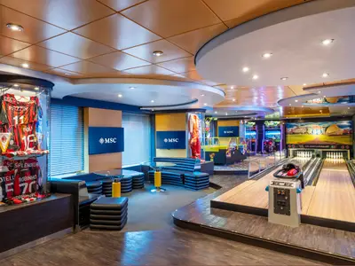Ein Blick in die lebhafte Sport Fun Bar der MSC Splendida mit Bowlingbahnen, Arcade-Automaten und Vitrinen mit Sport-Memorabilien. Moderne Sitzbereiche und MSC-Bildschirme sind ebenfalls zu sehen.