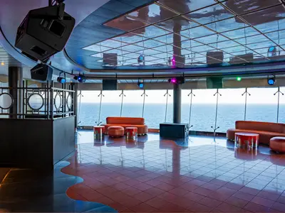 Die Club 33 Disco der MSC Splendida. Moderne Tanzfläche, orange Sofas, Meerblick. Spiegeldecke mit Lichtern. Ohne Personen.