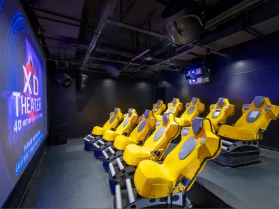 Das 4D XD Theater an Bord der MSC Splendida zeigt Reihen gelber Motion-Sitze vor einer großen Leinwand mit einem XD Theater-Logo. Deckenbeleuchtung und Technik sind sichtbar.