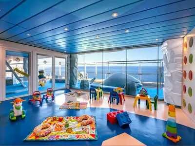 Der farbenfrohe Kids & Baby Club "Il Polo Nord" an Bord der MSC Splendida, mit Spielzeug und Tischen. Grosse Fenster bieten Meerblick.