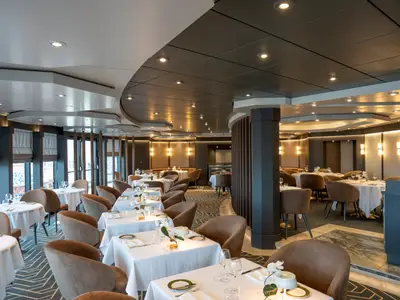 Elegantes Restaurant an Bord der MSC Splendida mit gedeckten Tischen, braunen Stühlen und stilvoller Beleuchtung. Große Fensterfronten prägen den modernen Raum. Ohne Personen.