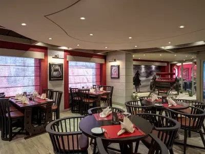 Ein thematisches Western-Restaurant namens Butcher's Cut an Bord der MSC Splendida mit vielen leeren Tischen, bereit für Gäste. Die Einrichtung ist rustikal mit roten Wänden und Pferde-Wandbildern.