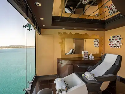 Ein luxuriöses Nagelstudio im MSC Aurea Spa der MSC Splendida mit einem Pedikürestuhl und grossen Fenstern, die einen weiten Blick auf das türkisblaue Meer und die Küste freigeben.