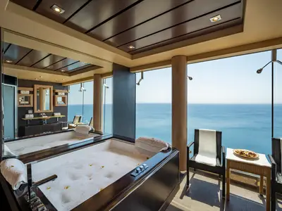 Luxuriöser Spa-Bereich im MSC Aurea Spa an Bord der MSC Splendida. Zwei Sprudelbäder mit Meerblick durch Panoramafenster. Elegante Einrichtung mit dunklem Holz, Spiegeln und Handtüchern.